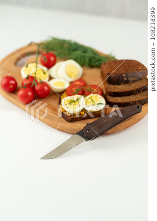 Folding pocket knife and cutting sandwiches. Kitchen cutting board. Making sandwiches. Slicing sandwiches. 108218399