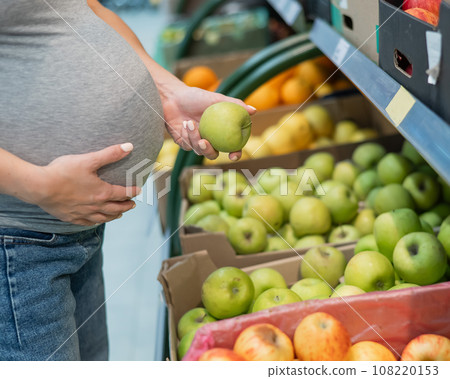 Pregnant woman chooses apples in the store. Pregnant woman chooses apples in the store. 108220153