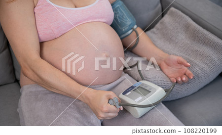 Close-up of the belly of a pregnant woman measuring blood pressure with a tonometer. Hypotension. Close-up of the belly of a pregnant woman measuring blood pressure with a tonometer. Hypotension. 108220199