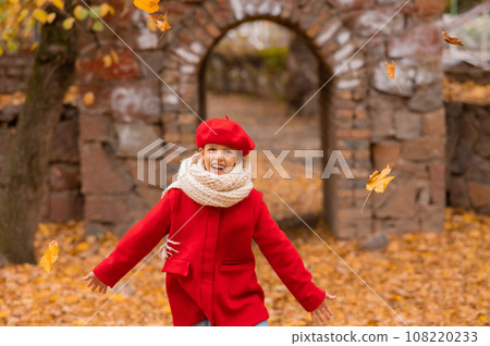 Happy caucasian girl in a red coat and beret walks in the park in autumn. Happy caucasian girl in a red coat and beret walks in the park in autumn. 108220233