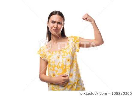 young woman with straight black hair in a yellow sundress with a print pattern shows her strength young woman with straight black hair in a yellow sundress with a print pattern shows her strength 108220300