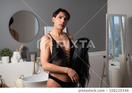 Homosexual preening in front of the mirror. A transgender man combing a wig. Homosexual preening in front of the mirror. A transgender man combing a wig. 108220346