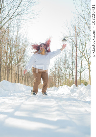 Smiling plump redhead woman jumping in park in winter.  108220431