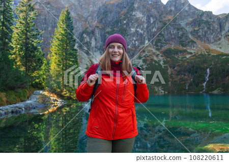 Tourist hiker woman backpacker on rock enjoying near the view of mountain lake Morskie Oko in Tatra National Park, Poland. 108220611