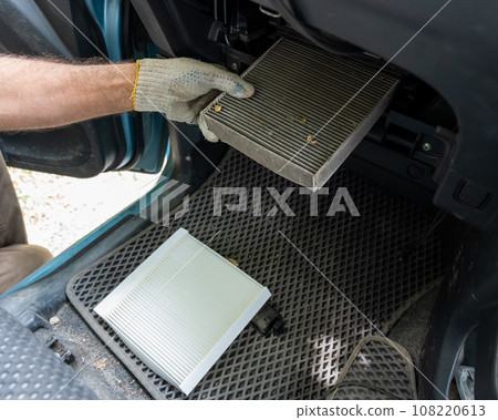A mechanic changes the cabin air filter of a car. A mechanic changes the cabin air filter of a car. 108220613
