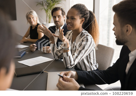 Positive engaged young African manager woman talking to colleagues Positive engaged young African manager woman talking to colleagues 108220659