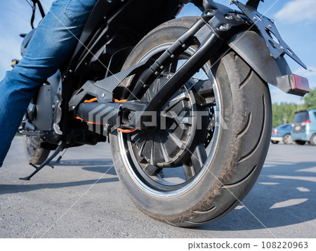 Close-up of the rear wheel with the engine of an electric motorcycle. Close-up of the rear wheel with the engine of an electric motorcycle. 108220963