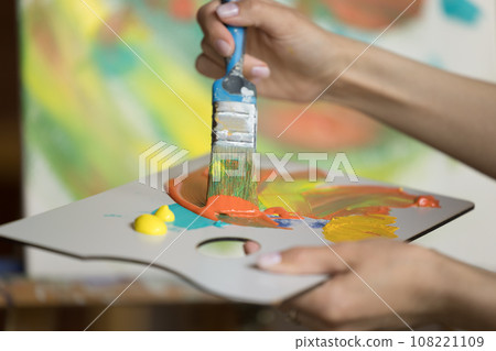 Unrecognizable female painter mixing colors, painting indoors 108221109