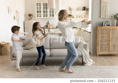 Happy mother dancing with two children at home Happy mother dancing with two children at home 108221133