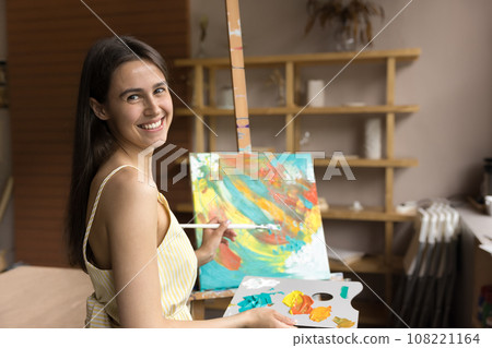 Smiling young woman painter posing in workshop Smiling young woman painter posing in workshop 108221164