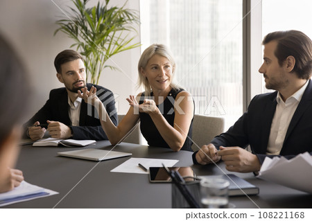 Positive confident mature business woman speaking to younger project partners 108221168