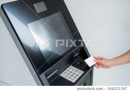 A faceless woman inserts a credit card into an ATM. Close-up of a woman's hands using an ATM machine. A faceless woman inserts a credit card into an ATM. Close-up of a woman's hands using an ATM machine. 108221197