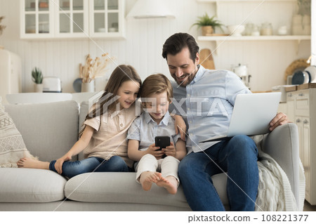 Father and little children using smartphone and laptop 108221377