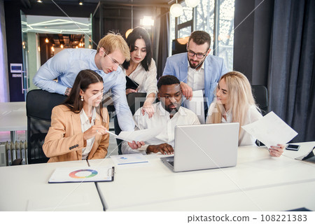 Inspired international male and female colleagues working together under their joint project on the computer in the modern office room. 108221383