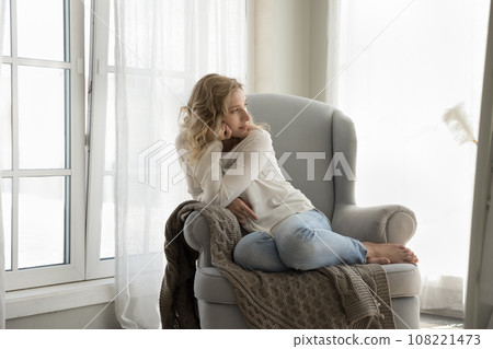 Young pensive lady relaxing alone at home Young pensive lady relaxing alone at home 108221473
