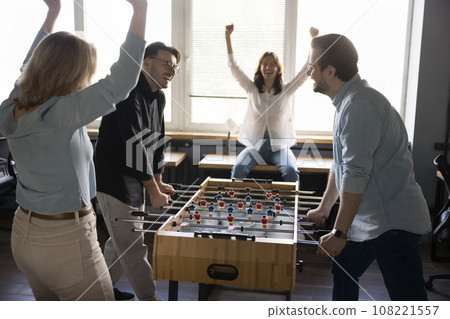 Teammates play table soccer in office during break Teammates play table soccer in office during break 108221557