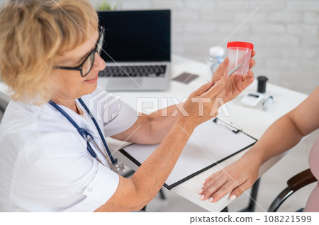 The doctor explains to a pregnant patient how to pass a urine test. 108221599