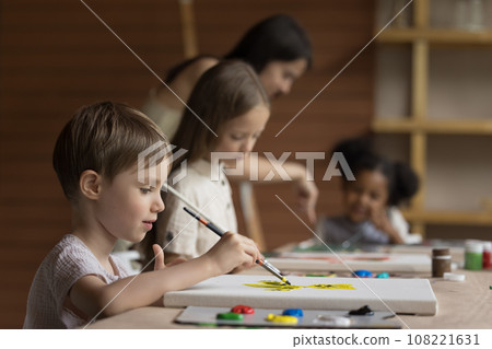 Pretty pupil boy painting during group class 108221631