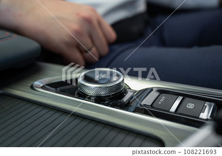 Close-up of a man's hands on the automatic transmission of a modern car.  108221693