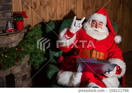 Happy santa claus remotely wishes merry christmas by video chat on a laptop Happy santa claus remotely wishes merry christmas by video chat on a laptop 108221766