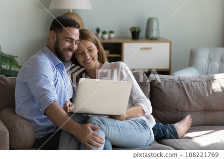 Happy joyful attractive husband and wife using laptop at home Happy joyful attractive husband and wife using laptop at home 108221769