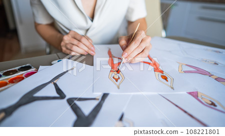 Faceless woman draws watercolor sketches of sportswear. Close-up of the hands of a fashion designer. Faceless woman draws watercolor sketches of sportswear. Close-up of the hands of a fashion designer. 108221801