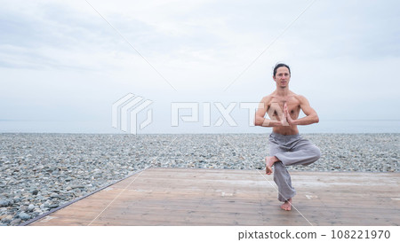 Caucasian man with naked torso practicing wushu on the seashore. Caucasian man with naked torso practicing wushu on the seashore. 108221970