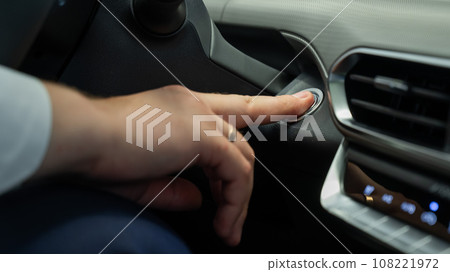 A man presses the car engine start button.  108221972