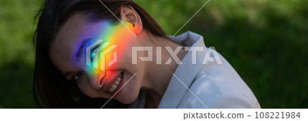 Portrait of caucasian woman with rainbow beam on her face outdoors. 108221984