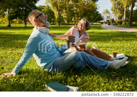 Senior loving family laughing while relaxing on green lawn grass in park 108222872