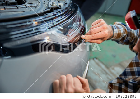 Cropped shot of mechanic applying protective film on headlight 108222895