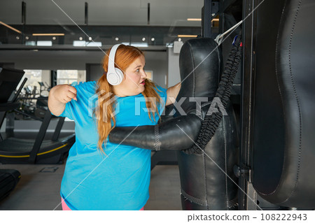 Overweight woman doing punching exercises boxing at gym Overweight woman doing punching exercises boxing at gym 108222943