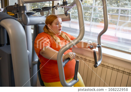 Tired sweaty obese woman breathing hard training at gym 108222958