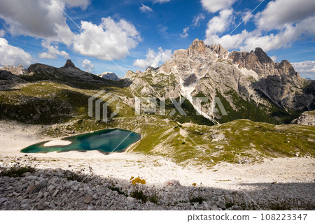 White sandy-rocky slope descends to shore of small lake in Laghi dei piani area with emerald water White sandy-rocky slope descends to shore of small lake in Laghi dei piani area with emerald water 108223347