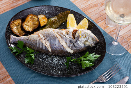 Dorada fish baked with lemon served with vegetable garnish Dorada fish baked with lemon served with vegetable garnish 108223391