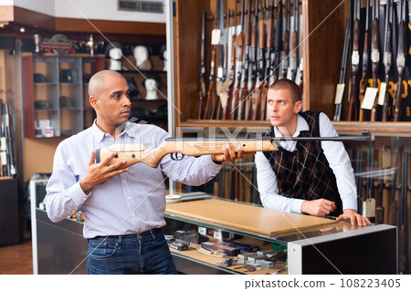 Two adult men choosing pneumatic weapon in military store Two adult men choosing pneumatic weapon in military store 108223405