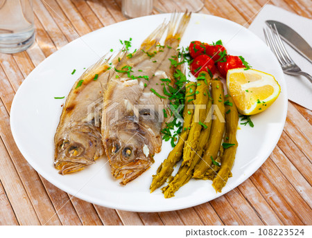 Fried roosterfish with asparagus, tomatoes and lemon 108223524