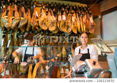 Young woman and man in uniform selling jamon Young woman and man in uniform selling jamon 108223650