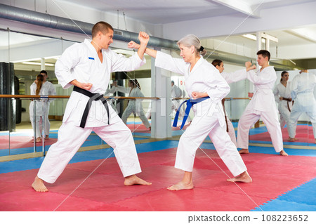 Man and senior woman in kimono sparring during group karate training 108223652