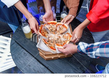 Close up human hands taking slices of hot tasty italian pizza from cardboard box at the party. 108223712