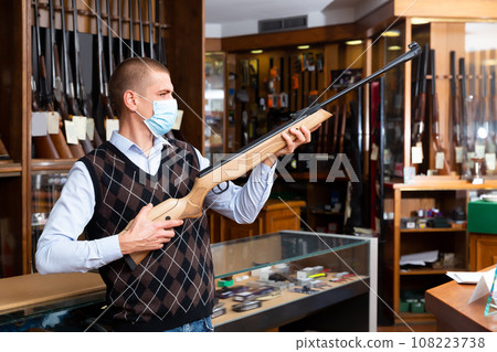 Focused gun shop salesman in protective mask Focused gun shop salesman in protective mask 108223738