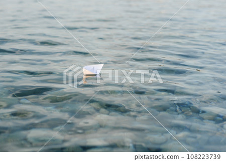 Origami paper boat sails on the surface of water 108223739