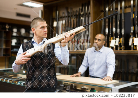 Man choosing hunting break barrel rifle in gun shop Man choosing hunting break barrel rifle in gun shop 108223817