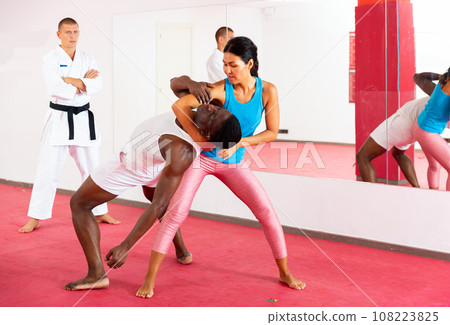 Active girl conducts painful grip on self-defense training in gym Active girl conducts painful grip on self-defense training in gym 108223825