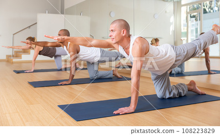 Man practicing Dandayamna Bharmanasana during group yoga training Man practicing Dandayamna Bharmanasana during group yoga training 108223829