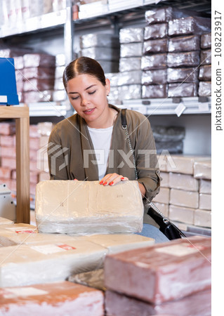Female customer chooses briquettes with white clay in specialized store 108223917