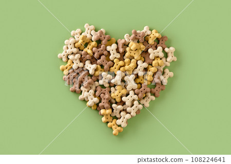 Dry dog food in heart shape on green background. Healthy organic nutrition for pets 108224641