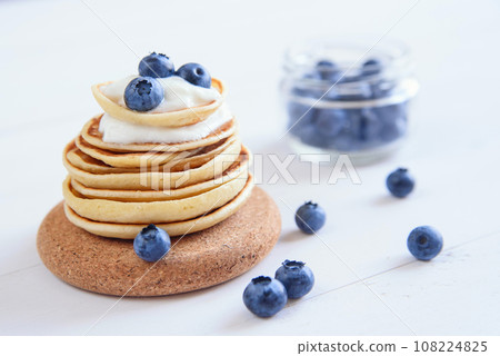 Delicious homemade pancakes with yogurt and fresh blueberries on white wooden background. 108224825