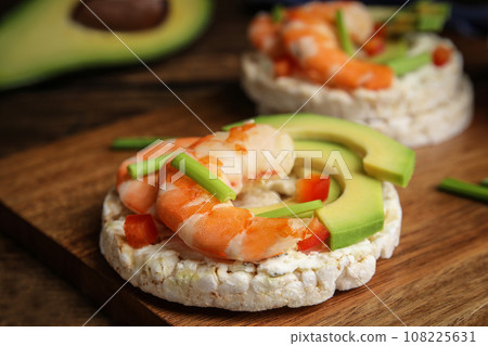 Puffed rice cakes with shrimps and avocado on wooden board, closeup Puffed rice cakes with shrimps and avocado on wooden board, closeup 108225631