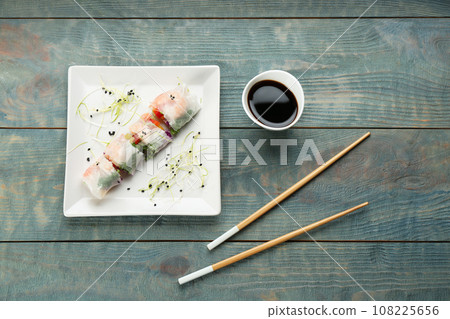 Delicious rolls wrapped in rice paper on light blue wooden table, flat lay 108225656